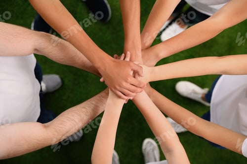 Preview: Group of volunteers joining hands together outdoors, top view