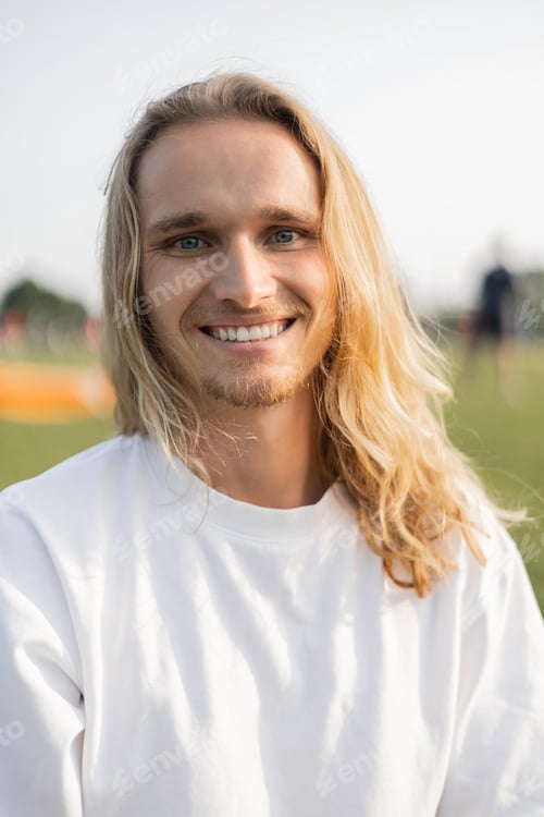 Preview: portrait of young and cheerful yoga man in white cotton t-shirt smiling at camera outdoors