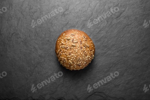 Preview: Multi seed bread bun on black slate background.