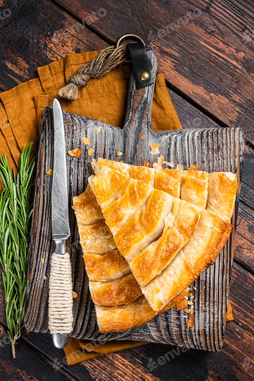 Preview: Homemade greek spanakopita pie with organic cheese on wooden board. Wooden background. Top view