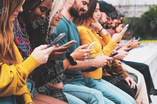 Preview: Group of young people using smartphone outdoors