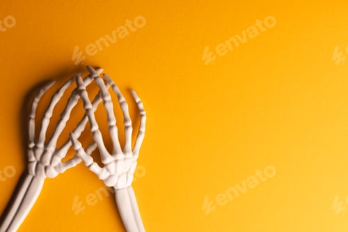 Preview: Plastic skeleton hands with copy space on yellow background
