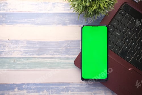 Preview: smart phone with empty screen, laptop on wooden background