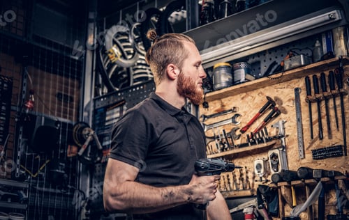 Preview: Red head bearded bicycle mechanic holds screwdriver.