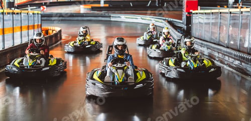 Preview: Young man in a helmet leading a group of racers in a go-kart race on an indoor track.
