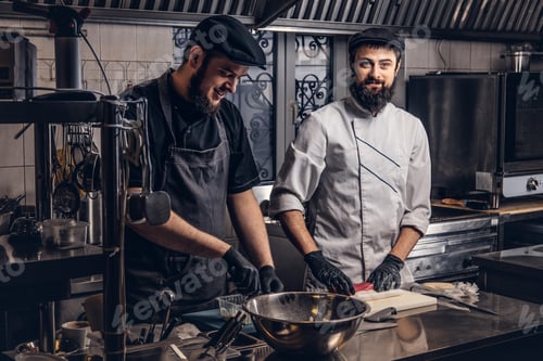 Preview: Two smiling bearded cooks dressed in uniforms preparing sushi in the kitchen.