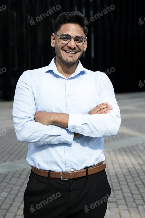 Preview: Smiling businessman arms crossed wearing glasses. Cheerful executive laughing in the street.
