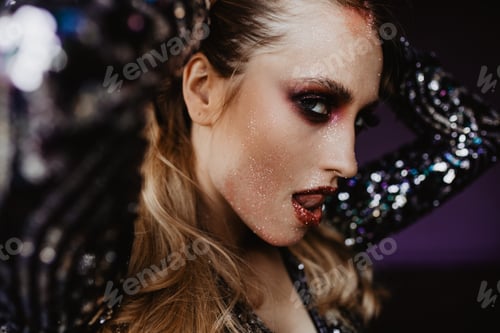 Preview: Refined woman in sparkle attire posing on dark background. Close-up portrait of sensual white lady