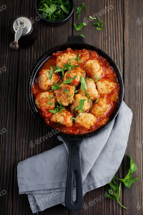 Preview: Meatballs in tomato sauce garlic and parsley in an iron frying pan on a dark brown wooden background