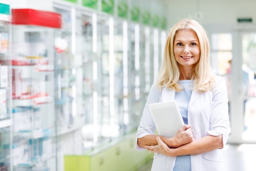 Smiling Woman Holding Tablet in Pharmacy Setting