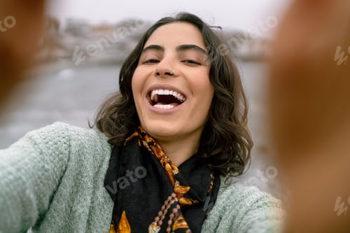 Preview: Young woman taking a selfie at the beach in winter