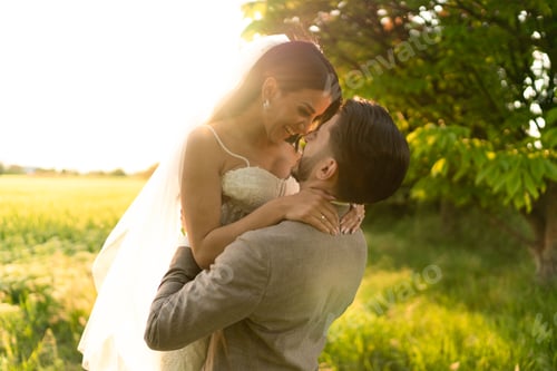 Preview: The groom lifts up the bride at sunset