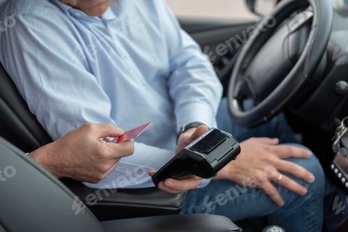 Preview: unrecognizable cab driver holding a bank payment terminal to process credit card payment purchases