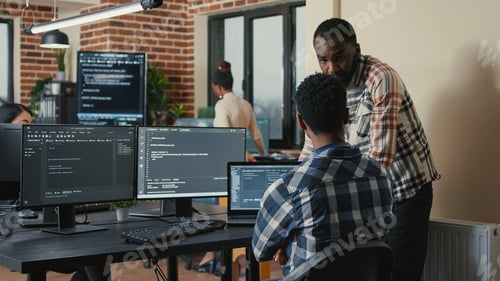 Preview: Software developer writing code on laptop and computer keyboard looking at multiple screens