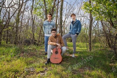 Preview: A band of young artists poses for a photo into a forest.