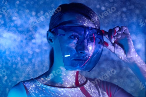 Preview: Confident young woman adjusting futuristic glasses against colorful background