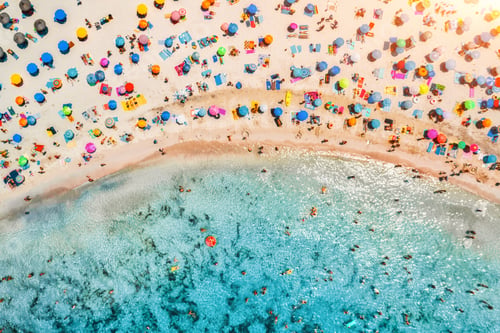 Preview: Aerial view of sandy beach with umbrellas and sea at sunset