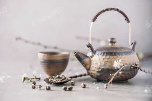 Preview: Black and brown iron teapot and tea cups, blossom flowers cherry branch on gray background. Top view