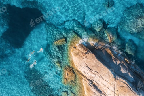 Preview: Aerial view of swimming people in blue sea, rocky beach, waves