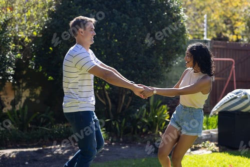 Preview: Young couple dancing and holding hands outdoors, enjoying sunny day together