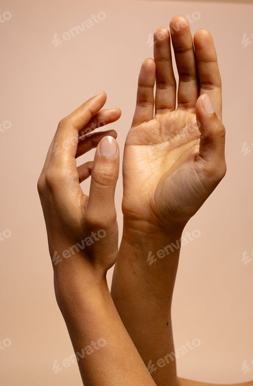 Preview: Crossed arms and reaching hands of biracial woman on pink beige background with copy space