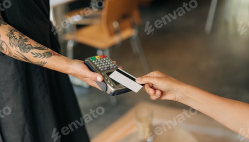 Preview: Woman paying with credit card at cafe, close-up of hands with credit card and credit card reader.