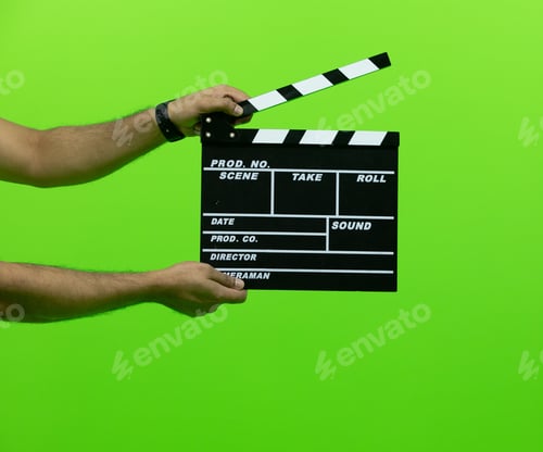 Preview: Men's hand holding camera slate for the filming isolated on green background