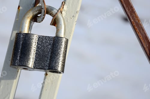 Preview: A large gray padlock hangs on a metal gate