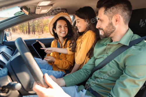 Preview: Happy family with daughter sitting in car and using digital tablet, checking online maps