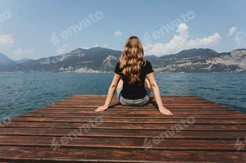 Preview: A young woman sitting near the river looking at stunning landscape. Relaxing and peaceful moment.