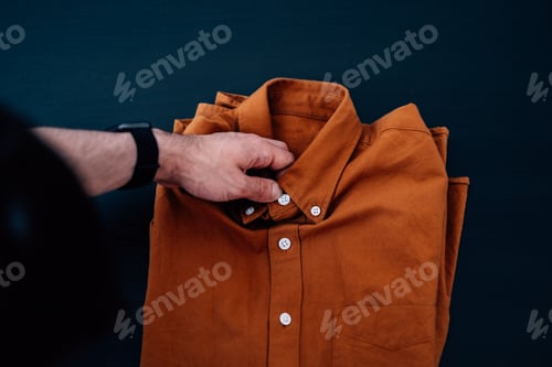 Preview: Folded Brown Button-Down Shirt on Dark Background