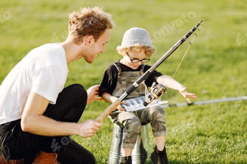 Preview: Young father teaching his little toddler son how to fish