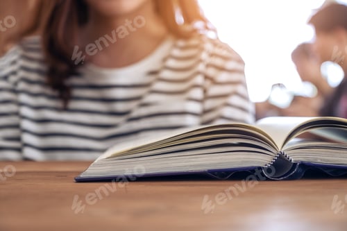 Preview: Closeup image of a woman and a book on wooden table