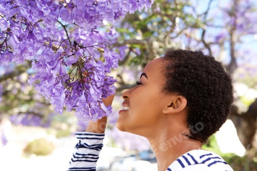 Preview: young black woman smelling flowers on tree