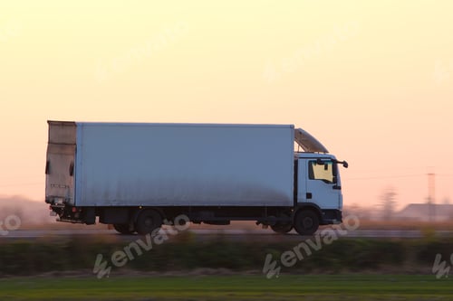 Preview: Cargo truck driving on highway hauling goods in evening