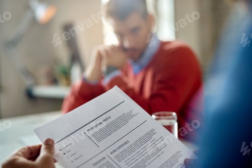 Preview: Close-up of a businessman reading candidate's resume during a job interview.