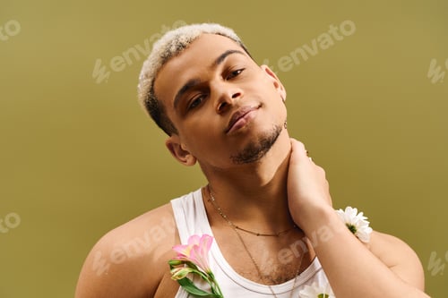 Preview: Stylish young man with dyed hair and floral accents poses in a studio