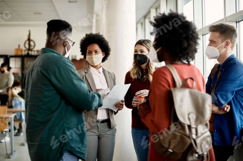 Preview: Group of students and their teacher wearing face masks while talking in hallway.