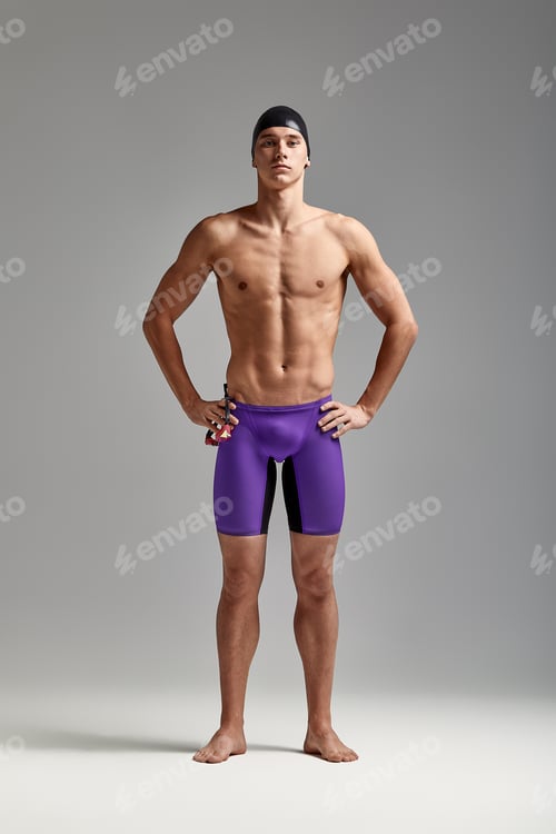 Preview: A man swimmer in goggles for swimming in full growth on a gray background, preparing an athlete for