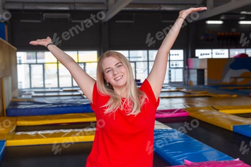 Preview: Fitness, fun, leisure and sport activity concept - Funny young woman smiling on a trampoline indoors