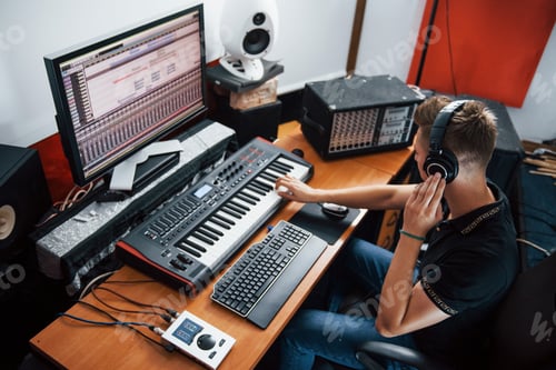 Preview: Sound engineer in headphones working and mixing music indoors in the studio