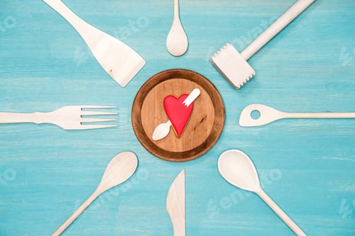 Preview: top view of various wooden kitchen utensils with pierced heart symbol on plate