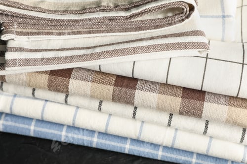 Preview: Stack of fabric napkins on black table, close up