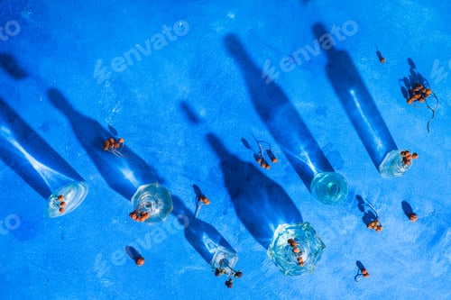 Preview: Glass bottle pattern with dried leaves and berries on a blue background with shadows and flares