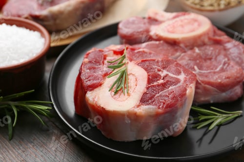 Preview: Pieces of raw beef, rosemary and salt on wooden table, closeup