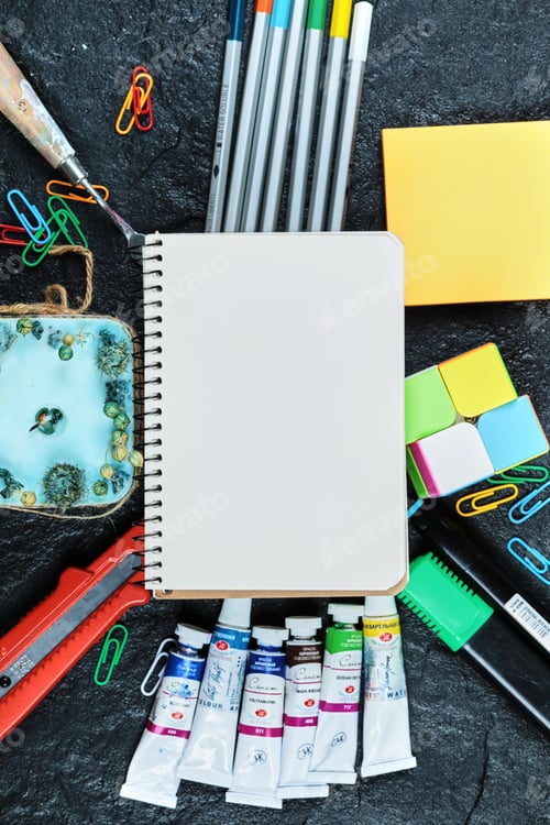 Preview: A little notebook with plenty of pencils and candle on dark background