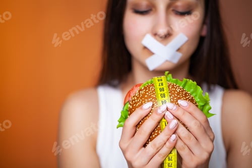 Preview: The concept of diet woman with sealed mouth keeps greasy burger