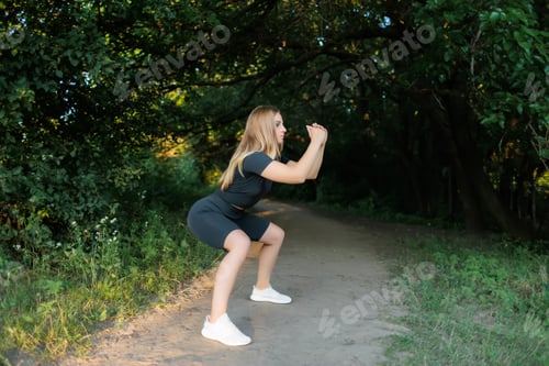 Preview: slender blonde girl doing squat exercises in the park