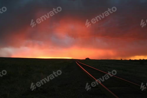 Preview: Dramatic sunset over railway tracks under a stormy sky