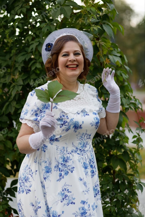 Preview: A woman in vintage clothes and a hat stands against the background of a fountain in an autumn park